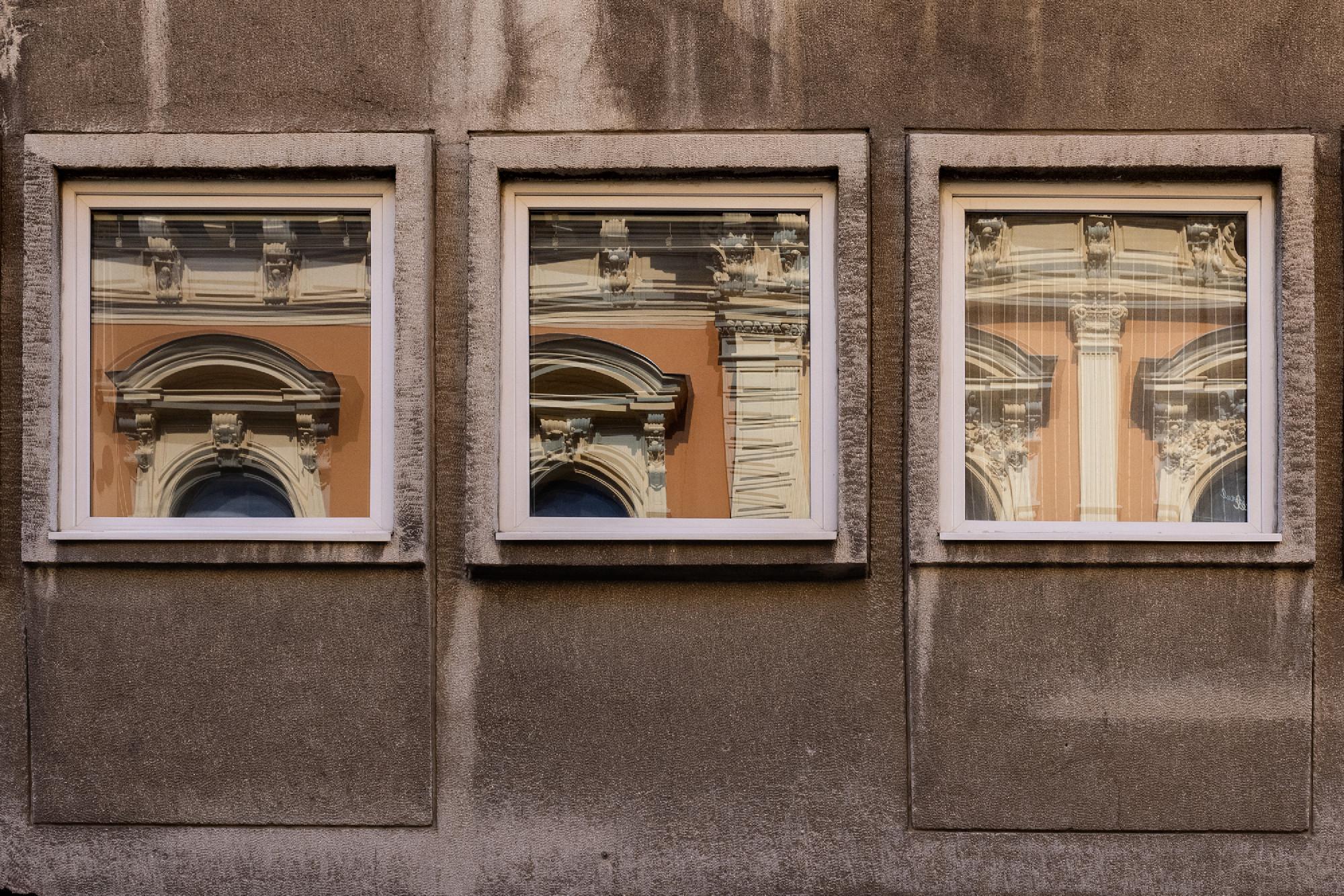 Fachada de vidro com reflexos de edifícios, em preto e branco